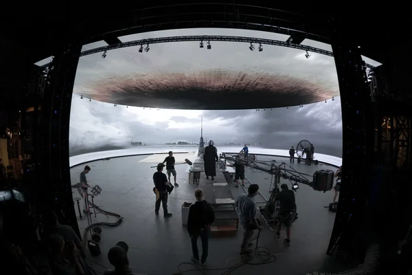 Scène de tournage de 'The Mandalorian' sur l'étendue Volume à Manhattan Beach, avec un grand écran LED incurvé affichant un paysage marin orageux et une équipe de production sur le plateau